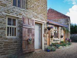 um edifício de tijolos com uma porta e uma janela em Manor House Dairy Cottage em Ayton