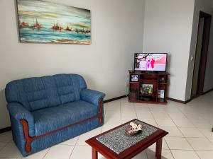 Apartamento 3 quartos Beira Mar في أنشيتا: غرفة معيشة مع أريكة زرقاء وتلفزيون