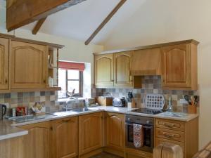 a kitchen with wooden cabinets and a sink at Henwood in East Meon