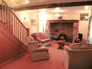 sala de estar con sofá y chimenea en Denhill Cottage en Chipstable