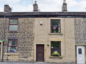 an old brick house with flowers in the window at Park View Cottage in Old Glossop