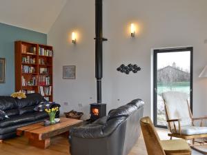 a living room with a black leather couch and a stove at Hygge in Eabost