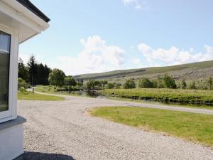 a house with a gravel road next to a river at March Cottage in Glenrossal