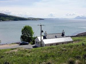 a house with a car parked next to a body of water at Cruary in Applecross