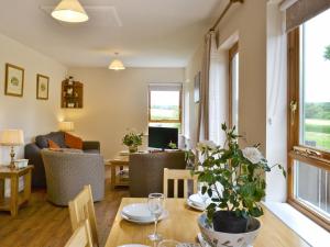 - un salon avec une table, des chaises et un canapé dans l'établissement Chestnut Cottage-27565, à Botesdale