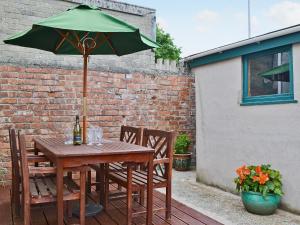 a wooden table with a green umbrella on a patio at Elens Place in Tywyn
