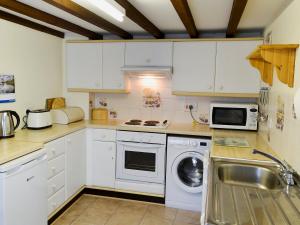 a kitchen with white cabinets and a sink and a dishwasher at Watercolour Cottage in Lerryn