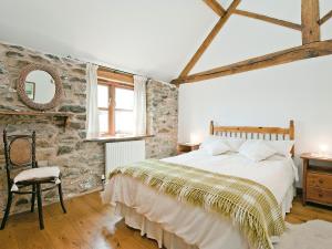 a bedroom with a large bed and a stone wall at Llofft Stabal in Llanerfyl