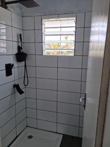 uma casa de banho com azulejos brancos, um WC e uma janela. em Résidence Le Verger, 2ch, Kribi em Kribi