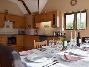 una cocina con una mesa con platos y copas de vino en Alfies Barn en Ambrosden
