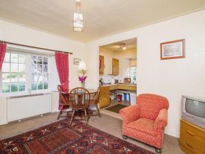 a living room with a table and a chair and a tv at Katys Cottage in Balnaboth