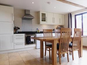 een keuken met een houten eettafel en stoelen bij Barn Owl Cottage in Sudbourne