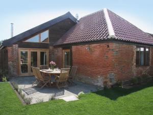 een stenen huis met een tafel en stoelen op een patio bij Barn Owl Cottage in Sudbourne