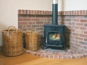 a fireplace with two baskets next to a brick wall at Barn Owl Cottage in Sudbourne