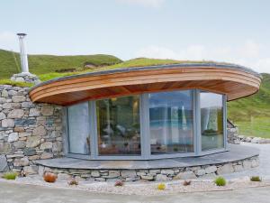 a circular building with a circular roof with a stone wall at Beach Bay Cottage in Mangersta