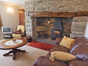 a living room with a couch and a stone fireplace at Rhiwgoch - Hw7449 in Harlech