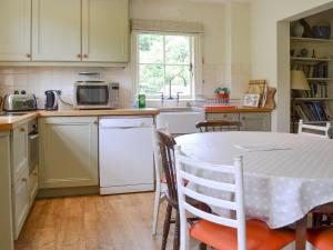 uma cozinha com uma mesa e uma cozinha com electrodomésticos brancos em Sunnybank em Saint Margaret