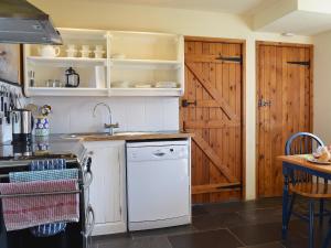 a kitchen with a white dishwasher next to a wooden door at TY NANT-oxl in Gwynfe