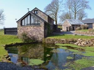 an old stone house with a pond in front of it at TY NANT-oxl in Gwynfe