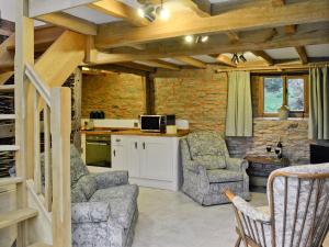 a living room with two chairs and a kitchen at Acorn Cottage in Croft