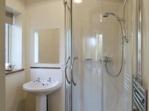 La salle de bains blanche est pourvue d'un lavabo et d'une douche. dans l'établissement Alby Bungalow, à Wetheral