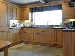 a kitchen with wooden cabinets and a large window at Misty View in Winchcombe