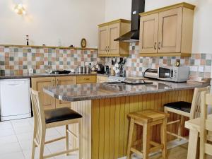a kitchen with wooden cabinets and a counter with stools at Dol Afon - Hw7588 in Llanuwchllyn