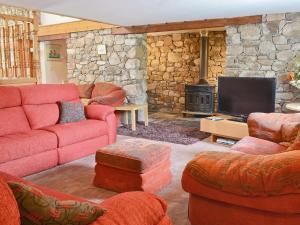 a living room with red furniture and a stone fireplace at The Barn in Waberthwaite