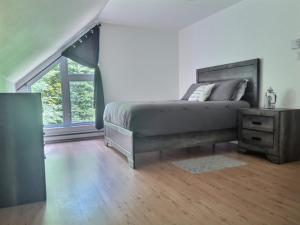 a bedroom with a bed and a dresser and a window at Chalet chez Antoine in Saint-Donat-de-Montcalm
