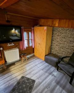 ein Wohnzimmer mit einem Flachbild-TV und einem Stuhl in der Unterkunft Privát POHODA in Nová ľubovňa