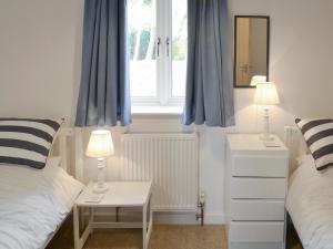 1 dormitorio con 2 camas y una ventana con cortinas azules en The Boat House, en Roughton