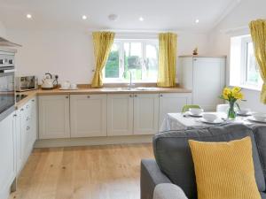 una cocina con armarios blancos y una mesa con almohadas amarillas en The Boat House, en Roughton
