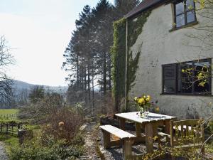 a table and bench in front of a building at Trowley Farmhouse in Llanbedr