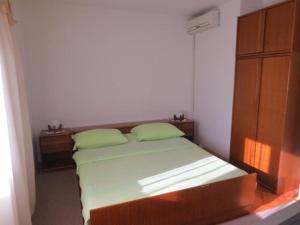 a bedroom with a bed with two green pillows at Rooms Juran in Sukošan
