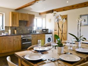 a kitchen with a wooden table with plates and wine glasses at The Granary-e3567 in Uggeshall