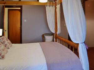 a bedroom with a bed with a canopy and curtains at Rose Cottage II in Scalby