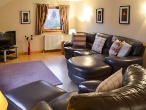 a living room with leather couches and a television at The Steadings Apartment in Kinlochmore