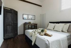 een slaapkamer met een groot bed met witte lakens en houten vloeren bij RED Appartamento immerso tra le mura bolognesi in Bologna