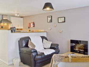 a living room with a leather chair and a table at The Cow Shed - Or5 in Henfynyw Upper