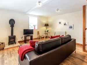 a living room with a leather couch and a wood stove at Hall Farm Cottage in Byers Green