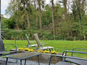 dos sillas y una mesa con flores en un parque en La Maison d'Anne-Marie, en Beauraing