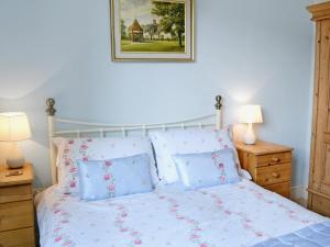 a bedroom with a white bed with blue pillows at Darwin Cottage - E4509 in Jevington
