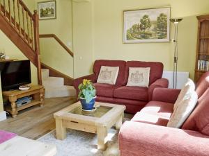 a living room with a red couch and a tv at Darwin Cottage - E4509 in Jevington