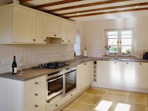 a white kitchen with white cabinets and a window at Lantern Cottage in Longborough