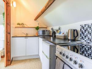 a kitchen with white cabinets and a stove top oven at Dunster Castle Loft - Uk13180 in Dunster