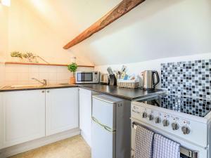 a kitchen with white cabinets and a stove top oven at Dunster Castle Loft - Uk13180 in Dunster