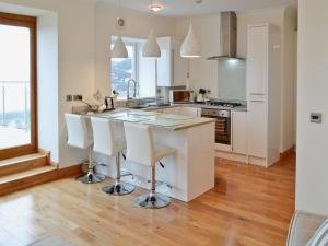 a kitchen with a large white island with white bar stools at Rockview in Cellardyke