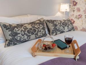 een dienblad met fruit en een glas wijn op een bed bij Brewery House Cottage in Bishop Middleham