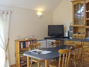 a kitchen with a table and chairs and a television at The Holt in Plockton