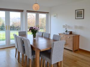 una mesa de comedor con sillas y un jarrón de flores en Carron House en Lochcarron